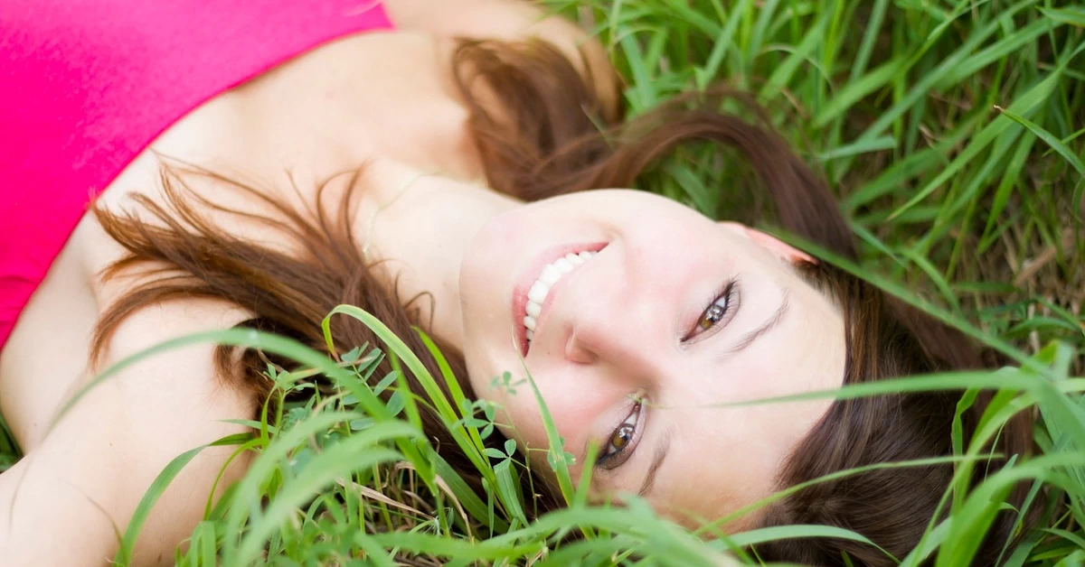 Confident woman lying on grass smiling